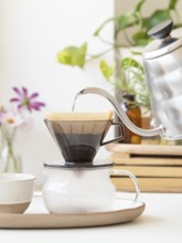 Hot water being poured from a modern kettle into a coffee filter, brewing a fresh cup of coffee