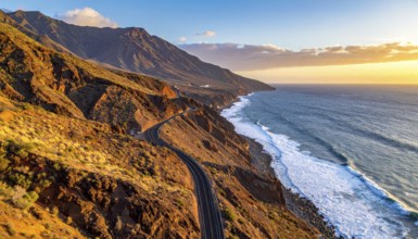Desert landscape converges with ocean along a rugged coastal area, shore break at cliffs, blue