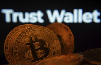 Dhaka, Bangladesh- 30 Sep 2025: Close-up of Bitcoin coins with the Trust Wallet logo visible on a