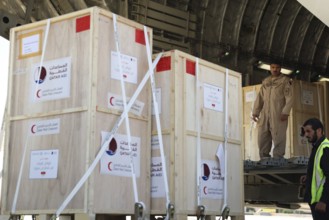 Members of the Qatari Air Force unload humanitarian aid supplies from a transport aircraft at