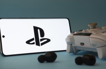 Dhaka, Bangladesh- 26 July 2025: A smartphone with a PlayStation icon next to a controller and