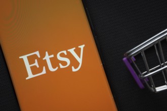 Dhaka, Bangladesh- 03 July 2025: A smartphone displaying the Etsy logo next to a miniature shopping