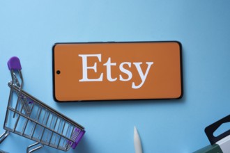 Dhaka, Bangladesh- 03 July 2025: Smartphone displaying Etsy logo with shopping cart on a blue