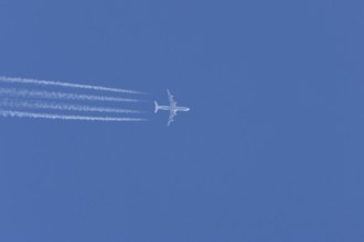 Airbus A340-300 jet aircraft of Lufthansa airlines in flight in a blue sky with vapour trails or