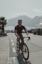Young man riding a racing bike on Lake Garda. Sunny weather and dolce vita