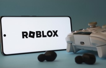 Dhaka, Bangladesh- 26 July 2025: A smartphone with a Roblox icon next to a controller and earbuds