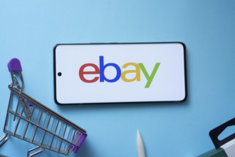Dhaka, Bangladesh- 03 July 2025: Smartphone displaying eBay logo with shopping cart on a blue