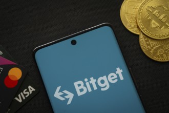 Dhaka, Bangladesh- 27 July 2025: Smartphone displaying Bitget logo surrounded by Bitcoin coins and