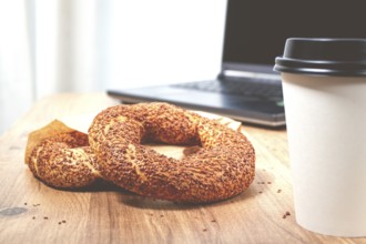 Simits with coffee on a wooden table, with a laptop, in a cozy working environment, snack,
