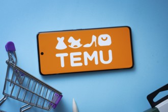 Dhaka, Bangladesh- 03 July 2025: Smartphone displaying Temu logo with shopping cart on a blue