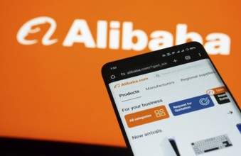Dhaka, Bangladesh- 03 July 2025: Smartphone displaying Alibaba web interface against Alibaba logo