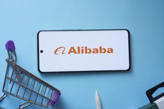 Dhaka, Bangladesh- 03 July 2025: Smartphone displaying Alibaba logo with shopping cart on a blue