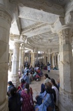 Indian woman praying between the white marble pillars in the Adinath temple in Ranakpur, Jain