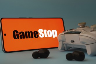 Dhaka, Bangladesh- 15 July 2025: A smartphone with a GameStop icon next to a controller and earbuds