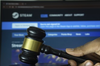 Dhaka, Bangladesh- 20 June 2025: A hand holds a gavel in front of a computer screen displaying