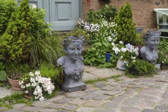 House entrance with blooming flowers, conifers and stone busts, Old Town, Husum, North Frisia,