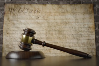 United states constitution on wall with gavel resting on table in front