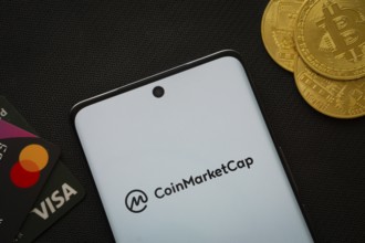 Dhaka, Bangladesh- 22 June 2025: Smartphone displaying Coinmarketcap logo surrounded by Bitcoin