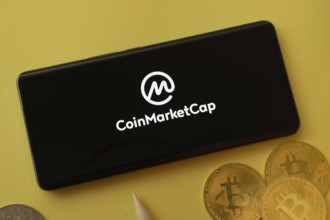 Dhaka, bangladesh- 12 June 2025: Coinmarketcap logo displayed on a smartphone with Bitcoin coins on