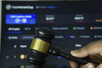 Dhaka, Bangladesh- 20 June 2025: A hand holds a gavel in front of a computer screen displaying