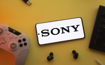 Dhaka, Bangladesh- 03 June 2025: Smartphone with Sony logo, game controller, and earbuds on a