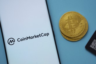 Dhaka, Bangladesh- 22 June 2025: Coinmarketcap logo on smartphone screen near Bitcoin coin and QR