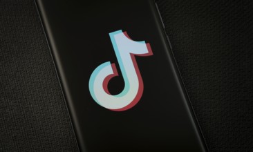 The logo of the TikTok is displayed on a smartphone screen