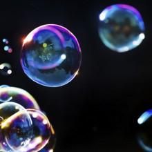 Iridescent soap bubbles in the colours of the rainbow against a black background, Recklinghausen,