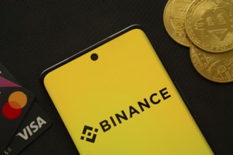 Dhaka, Bangladesh- 22 June 2025: Smartphone displaying Binance logo surrounded by Bitcoin coins and
