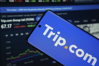 trello logo is displayed on a smartphone screen, with a stock graph webpage visible on a computer