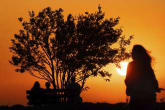People watching the sun set on the horizon from the summit of the Großer Feldberg in the Taunus,