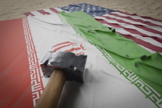 Large hammer, american and Iranian flags resting on desert sand