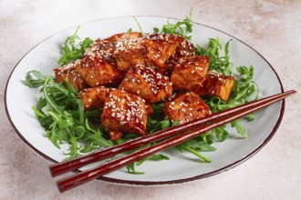 Fried salmon slices, teriyaki with sesame seeds, with arugula salad, top view