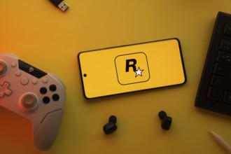 Dhaka, Bangladesh- 17 June 2025: Smartphone with rockstar games logo, game controller, and earbuds