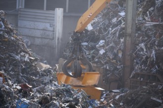 Hydraulic crane lifts scrap metal at the scrap yard