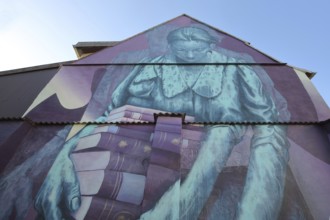 Mural Knowledge by Sokar Uno 2023, blue violet house wall, woman carrying a stack of books, books,