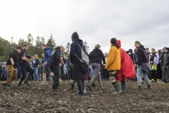 Festival visitors dance in the mud in front of the Atmos Stage at the Rock am Ring Festival on