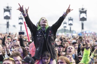 Festival visitor on shoulders with a French fries fork shaped like a hand at the Rock am Ring