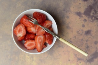 Sliced strawberries in hull with fork, Fragaria