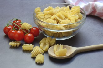 Italian pasta in glass bowl and cooking spoon, Radiatori variety