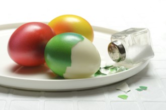 Easter eggs and salt shaker on plate, partially peeled