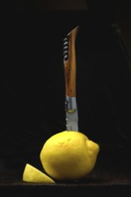 Lemon with knife in front of black background