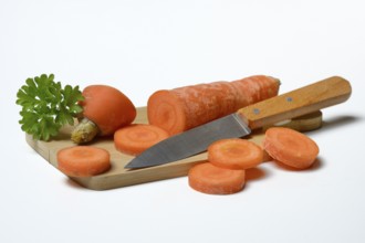 Carrot, carrot slices with kitchen knife on wooden board