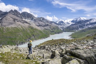 Mountaineer on a hiking trail at a blue mountain lake, reservoir Lac des Dix, behind mountain peak
