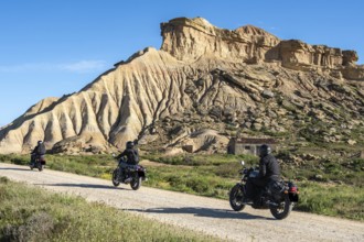 Biker riding motorcycle, gravel road, colorful rock formation, semi-desert, Bardena Blanca area,