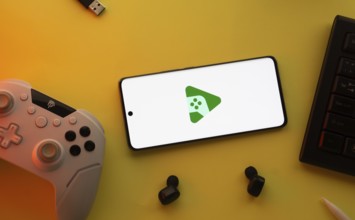 Smartphone with Google Play Games logo, game controller, and earbuds on a yellow background