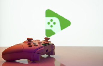 A close-up of a gamepad with the Google Play Games seen on screen in the background