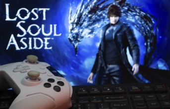 A close-up of a white gamepad with the Lost Soul Aside seen on screen in the background
