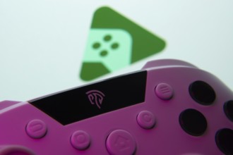 A close-up of a gamepad with the Google Play Games seen on screen in the background