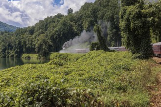 Steam from the Great Smoky Mountains Railroad hangs in the air as the train rounds a curve through